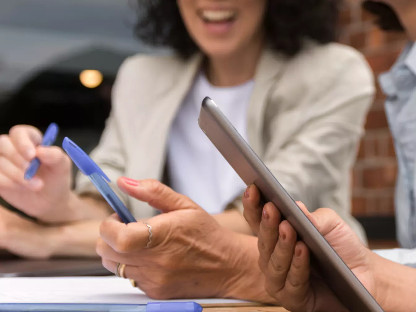 Two people with smartphone Mężczyzna w okularach i kobieta w biurze podczas biznesowej dyskusji, używając laptopów i tabletów.
